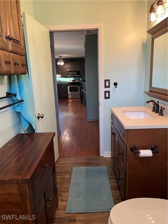 bathroom featuring hardwood / wood-style flooring, vanity, ceiling fan, and toilet