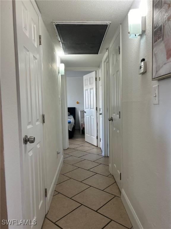 hallway featuring a textured ceiling and light tile patterned flooring