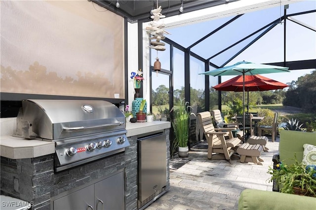 view of patio with a lanai, exterior kitchen, and grilling area