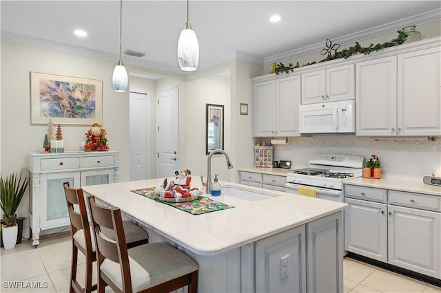 kitchen with decorative light fixtures, white appliances, a center island with sink, and sink