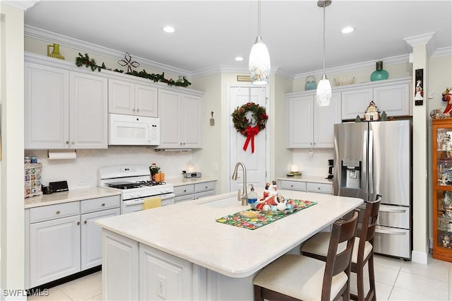 kitchen featuring sink, crown molding, pendant lighting, white appliances, and a center island with sink