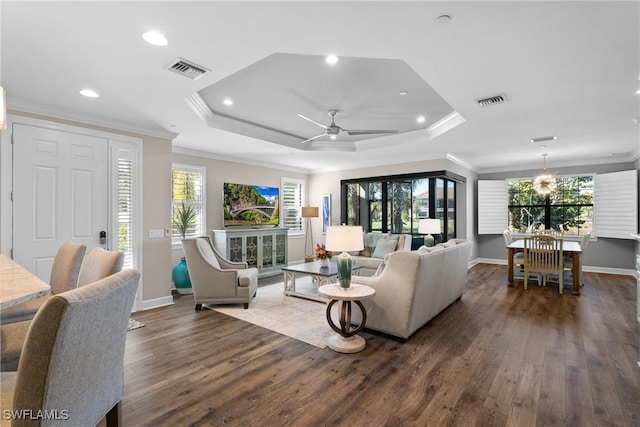 living room with dark hardwood / wood-style flooring, ceiling fan, a raised ceiling, and crown molding