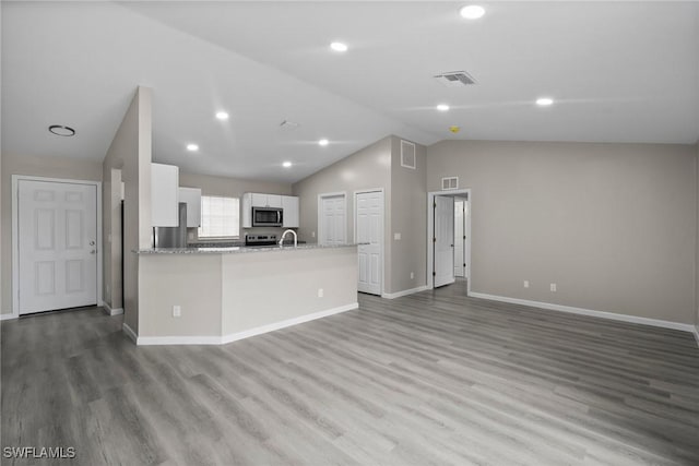 kitchen featuring kitchen peninsula, stainless steel appliances, vaulted ceiling, light hardwood / wood-style flooring, and white cabinets