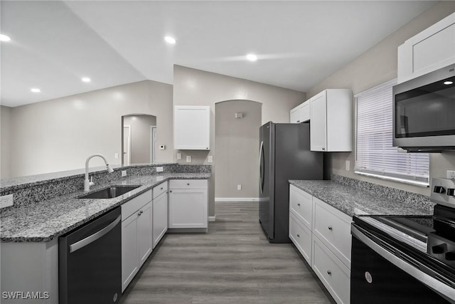 kitchen with appliances with stainless steel finishes, sink, dark hardwood / wood-style floors, white cabinetry, and lofted ceiling