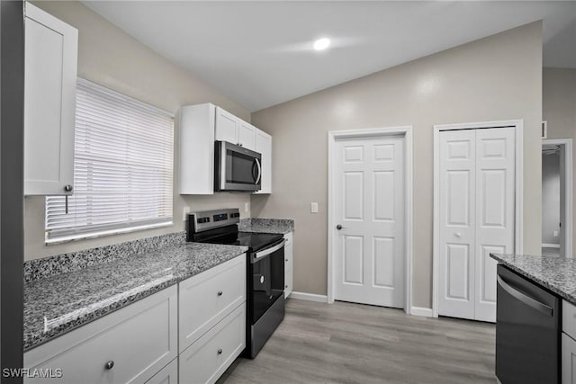 kitchen featuring light stone countertops, appliances with stainless steel finishes, lofted ceiling, white cabinets, and light wood-type flooring