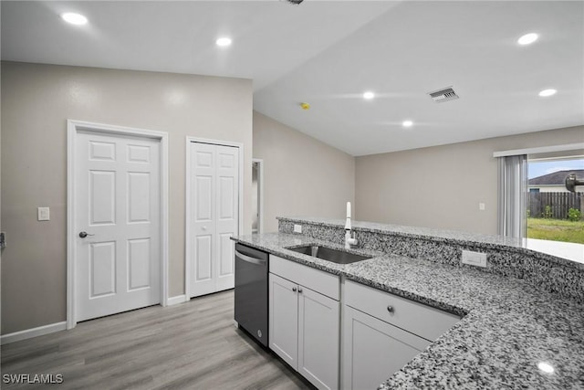 kitchen with white cabinetry, light stone countertops, dishwasher, sink, and vaulted ceiling