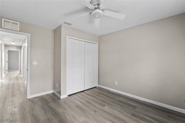 unfurnished bedroom with wood-type flooring, a closet, and ceiling fan