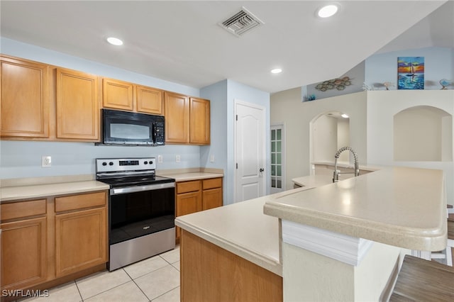 kitchen with a center island with sink, visible vents, light countertops, stainless steel range with electric stovetop, and black microwave