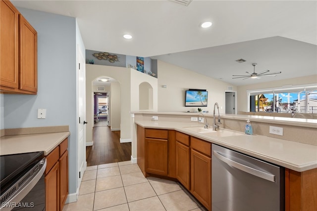 kitchen with a sink, stainless steel appliances, vaulted ceiling, and light countertops