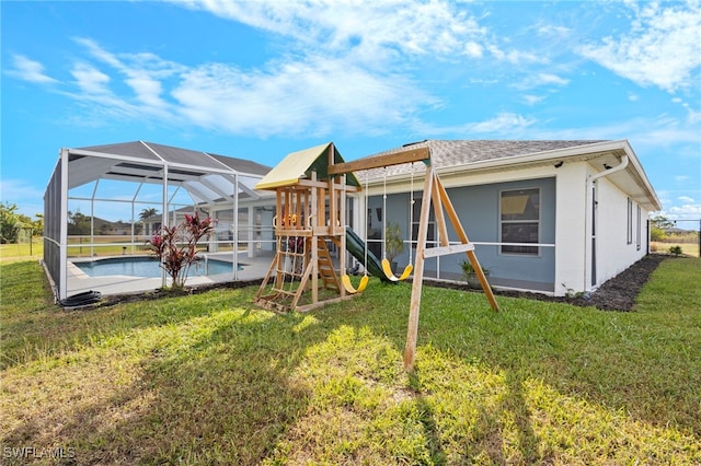 back of property featuring glass enclosure, a playground, an outdoor pool, a yard, and stucco siding