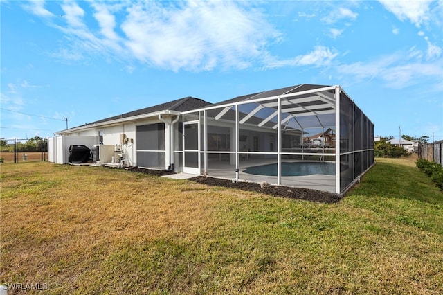 rear view of house with a lawn, a lanai, and an outdoor pool