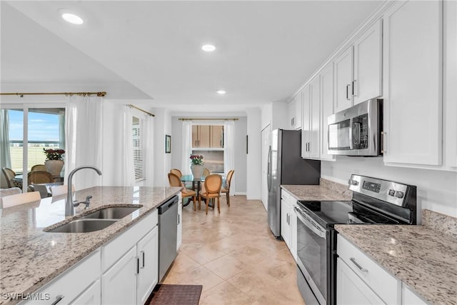 kitchen with light stone countertops, white cabinetry, sink, and stainless steel appliances