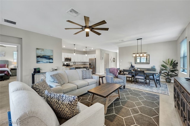 tiled living room featuring ceiling fan with notable chandelier