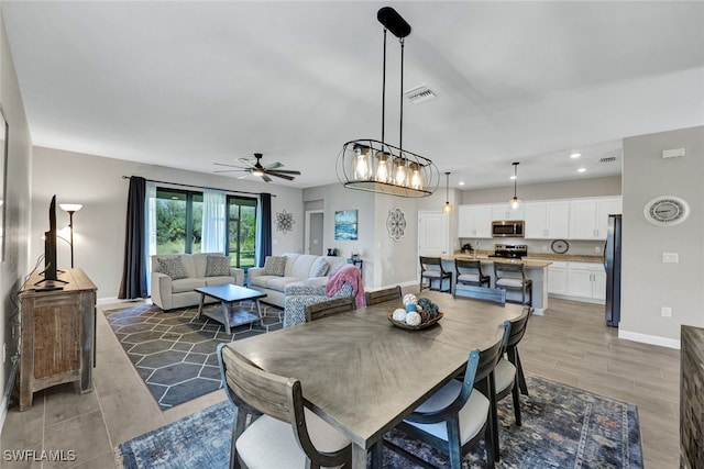 dining area featuring light hardwood / wood-style floors and ceiling fan with notable chandelier