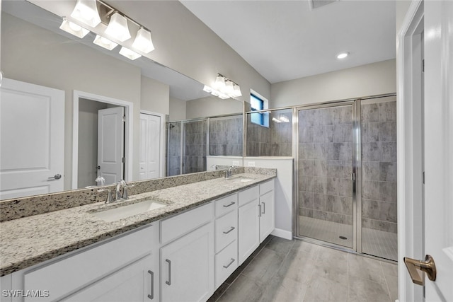 bathroom with wood-type flooring, vanity, and a shower with door