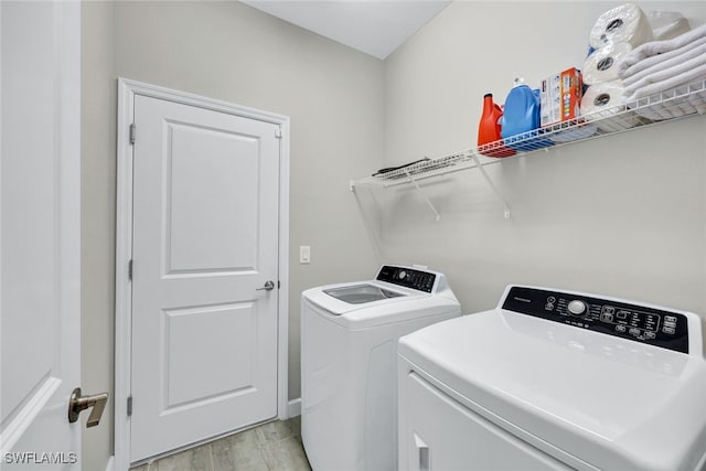 clothes washing area featuring washer and clothes dryer and light hardwood / wood-style flooring