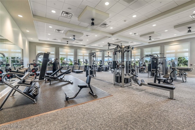 exercise room featuring a paneled ceiling, ceiling fan, and a healthy amount of sunlight