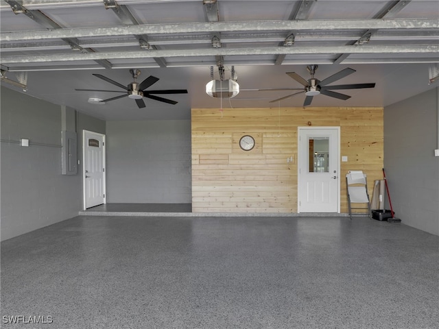 garage featuring ceiling fan, wood walls, electric panel, a garage door opener, and concrete block wall