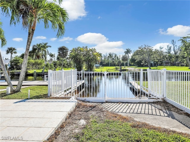 view of dock with a lawn and a water view