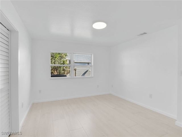 unfurnished room with baseboards and visible vents