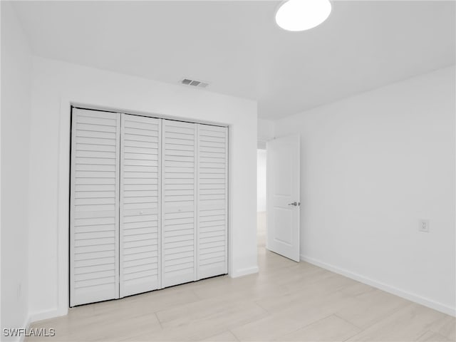 unfurnished bedroom with baseboards, visible vents, and a closet