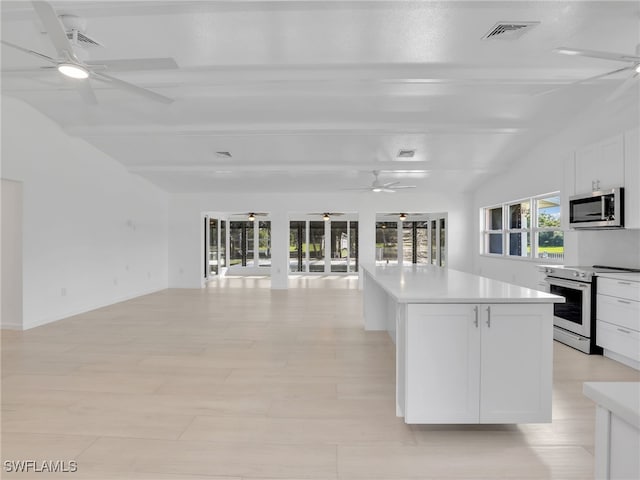 kitchen featuring visible vents, a center island, open floor plan, stainless steel appliances, and a ceiling fan