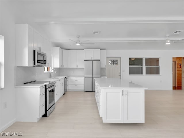 kitchen with a kitchen island, decorative backsplash, stainless steel appliances, a ceiling fan, and a sink