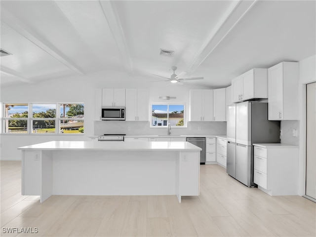 kitchen with a kitchen island, ceiling fan, a sink, light countertops, and appliances with stainless steel finishes