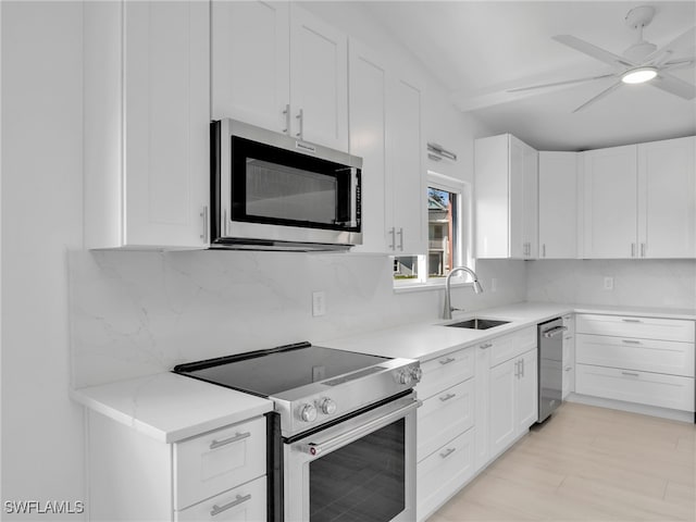 kitchen featuring a sink, white cabinetry, appliances with stainless steel finishes, decorative backsplash, and ceiling fan