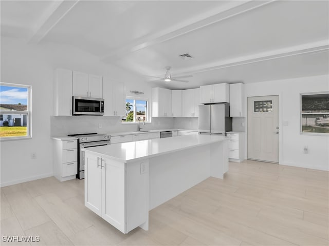 kitchen featuring visible vents, a center island, beam ceiling, stainless steel appliances, and a sink