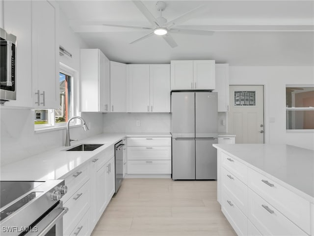 kitchen with white cabinetry, light countertops, appliances with stainless steel finishes, and a sink