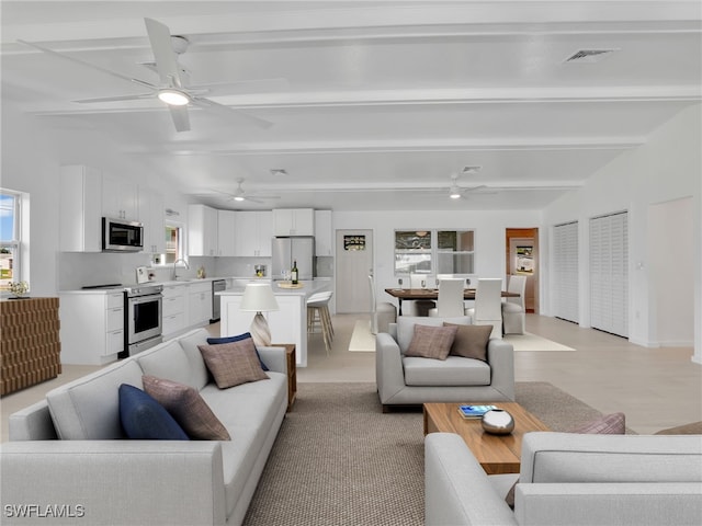 living area with beamed ceiling, baseboards, and ceiling fan