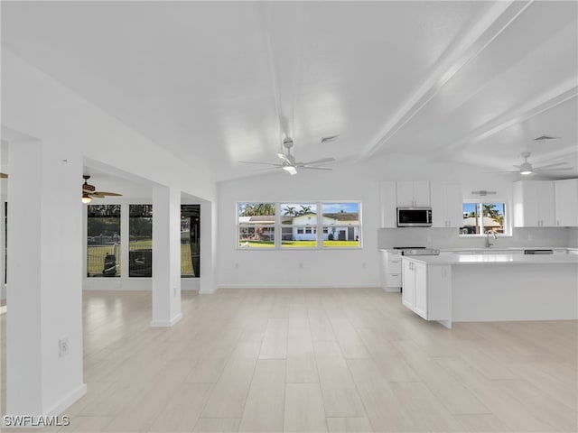 kitchen featuring ceiling fan, light countertops, white cabinets, stainless steel microwave, and open floor plan