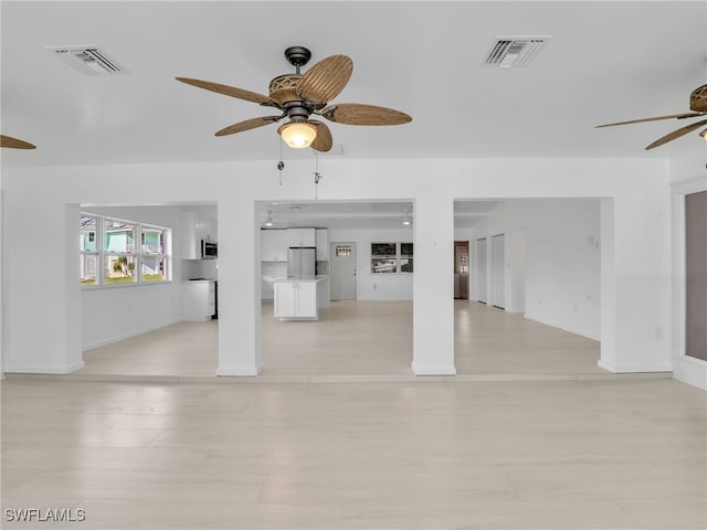 unfurnished living room featuring visible vents, baseboards, and a ceiling fan