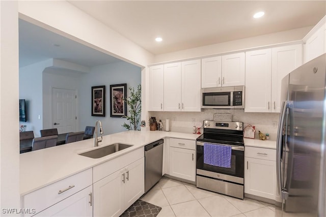 kitchen featuring kitchen peninsula, stainless steel appliances, white cabinets, and sink