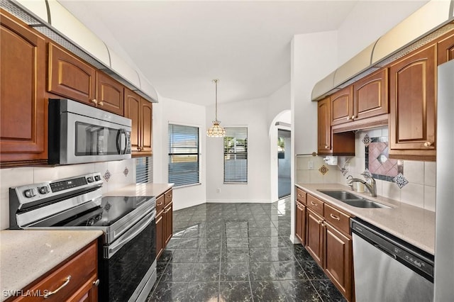 kitchen featuring backsplash, sink, hanging light fixtures, and appliances with stainless steel finishes