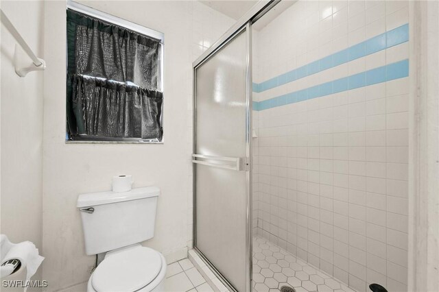 bathroom featuring tile patterned flooring, toilet, and an enclosed shower