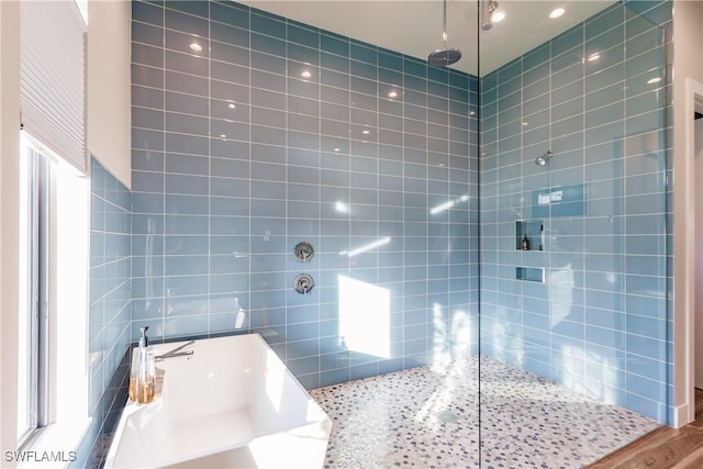 bathroom featuring tiled shower, hardwood / wood-style floors, plenty of natural light, and tile walls