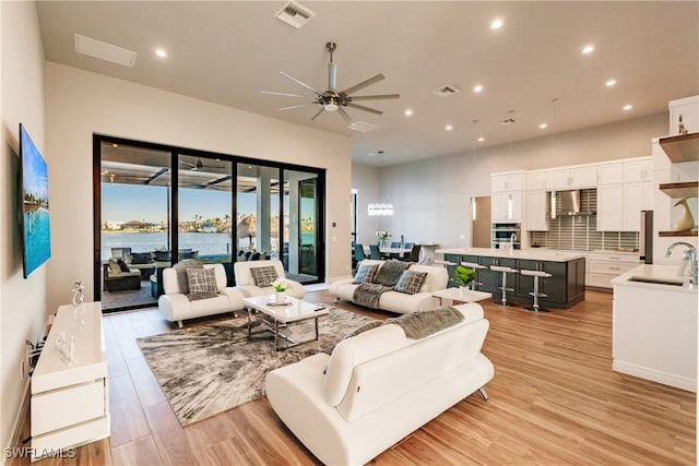 living room featuring light hardwood / wood-style floors, ceiling fan, and sink