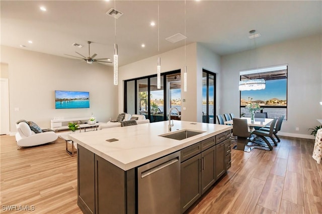 kitchen with ceiling fan, sink, stainless steel dishwasher, a kitchen island with sink, and light wood-type flooring