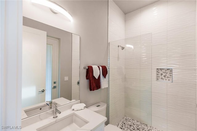 bathroom featuring vanity, toilet, and a tile shower