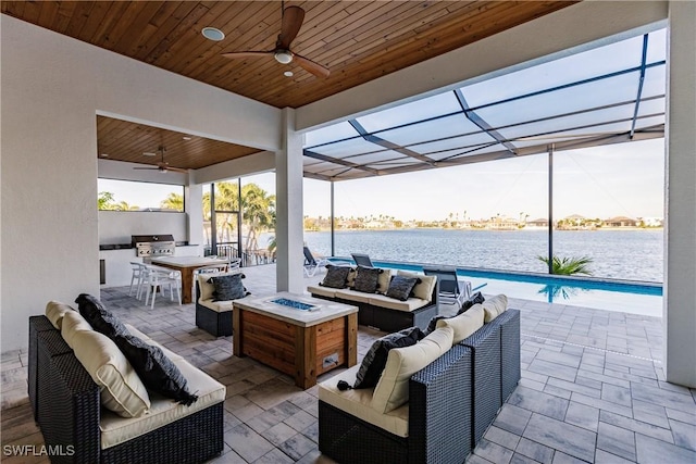 view of patio / terrace with area for grilling, ceiling fan, a water view, and an outdoor living space with a fire pit