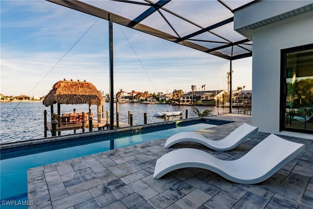 view of swimming pool with a boat dock, a water view, glass enclosure, and a patio area