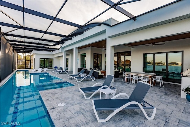 view of pool with glass enclosure, ceiling fan, a patio area, and outdoor lounge area