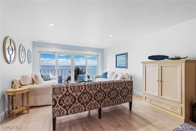 living room with light hardwood / wood-style floors and a water view