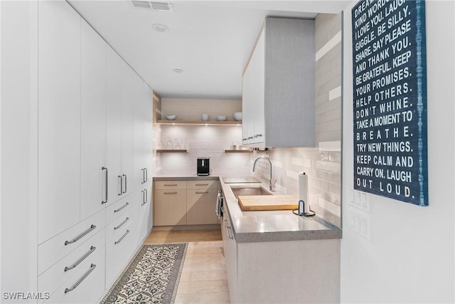 kitchen featuring white cabinetry, backsplash, and sink