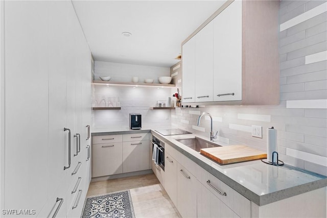 kitchen with oven, decorative backsplash, sink, white cabinets, and black electric cooktop