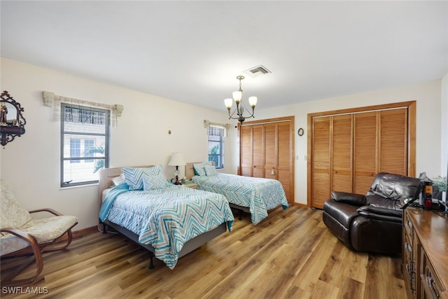 9940 Vanderbilt Dr, Naples, FL 34108 - bedroom featuring light wood finished floors, an inviting chandelier, two closets, and visible vents