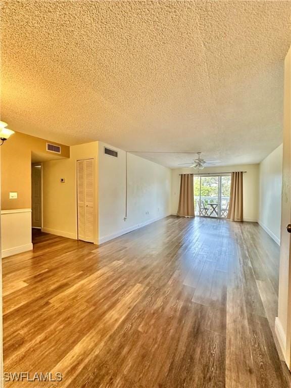 unfurnished living room with hardwood / wood-style floors, ceiling fan, and a textured ceiling