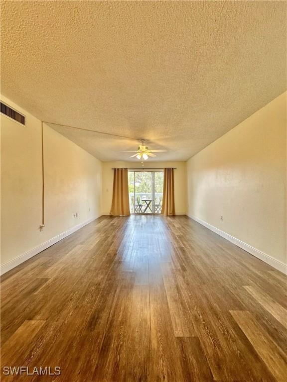 empty room with a textured ceiling, dark hardwood / wood-style floors, and ceiling fan